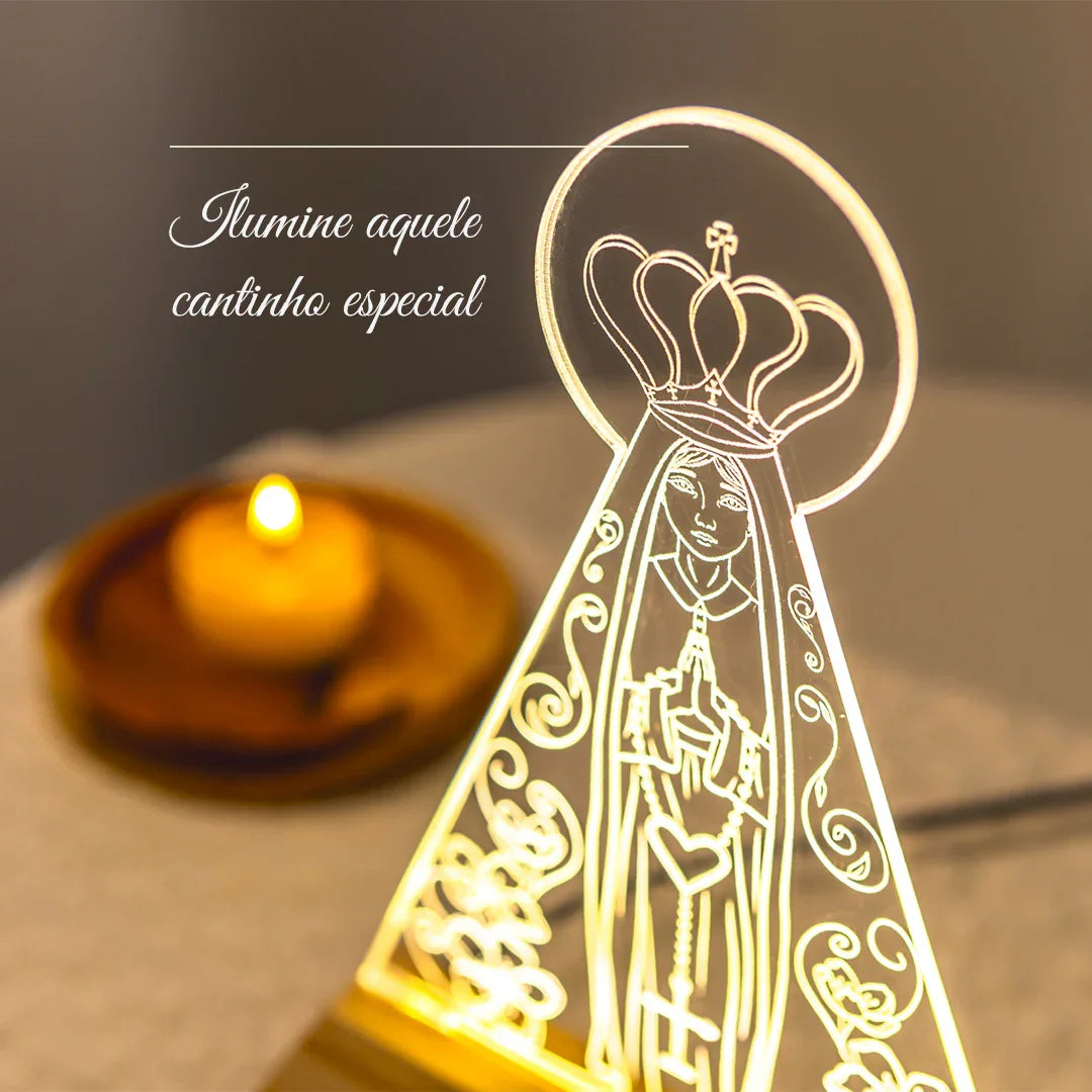 Luminária decorativa de Nossa Senhora Aparecida iluminada, com vela acesa ao fundo.