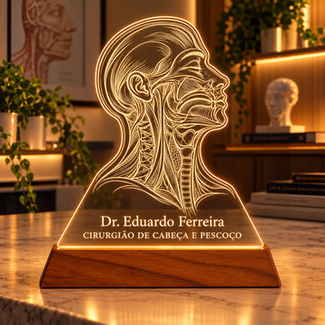 Luminária Cirurgião de Cabeça e Pescoço personalizada acesa, com perfil anatômico de cabeça e pescoço e o nome Dr. Eduardo Ferreira gravados em acrílico sobre base de madeira