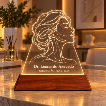Luminária Cirurgião Plástico personalizada acesa, com desenho de perfil feminino em linhas e o nome Dr. Leonardo Azevedo gravados em acrílico sobre base de madeira