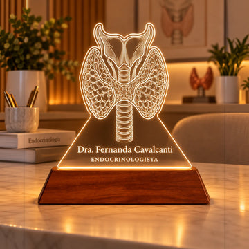 Luminária Endocrinologista personalizada acesa, com desenho de tireoide anatômica e o nome Dra. Fernanda Cavalcanti gravados em acrílico sobre base de madeira