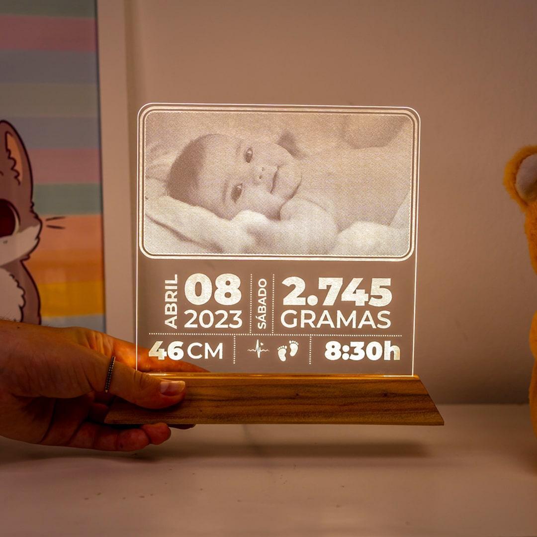 Luminária personalizada com foto de bebê, dados de nascimento e base de madeira em ambiente infantil.