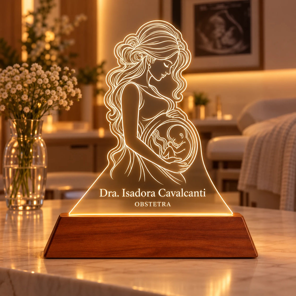 Luminária Obstetra Personalizada com desenho de gestante e bebê gravado no acrílico, nome Dra. Isadora Cavalcanti e especialidade OBSTETRA, sobre base de madeira com luz LED branco quente