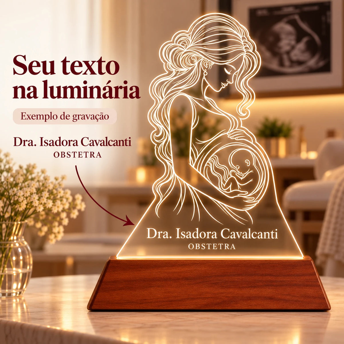 Seu texto na luminária: exemplo de gravação com o nome Dra. Isadora Cavalcanti e a especialidade OBSTETRA abaixo do desenho de gestante