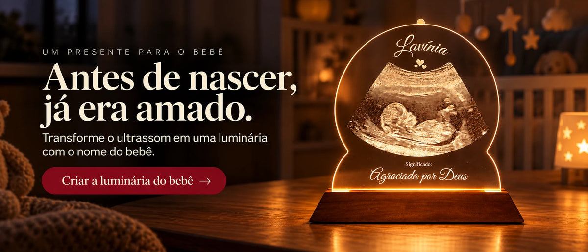Antes de nascer, já era amado. Luminária de ultrassom personalizada com o nome do bebê, acesa sobre a mesa. Crie a sua na Sentim.